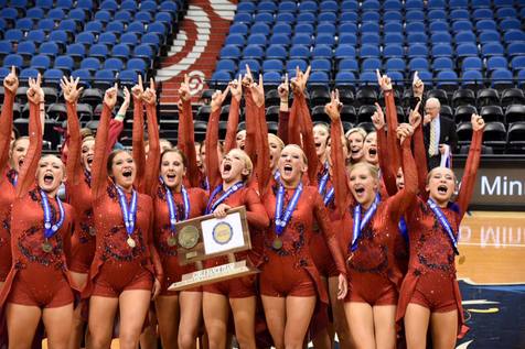 Lightning Dance Team celebrating with their medals and trophy, cheering on the court in red uniforms.
