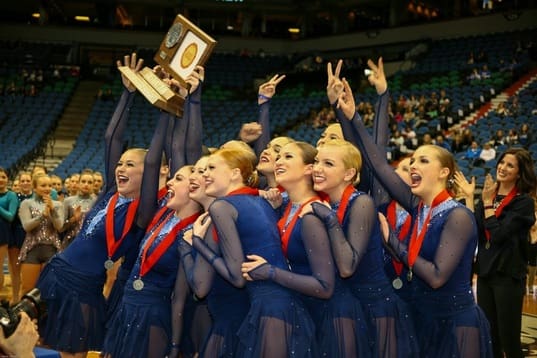 2014-2015 Lightning Dance Team celebrating with their trophy on the court in blue outfits.