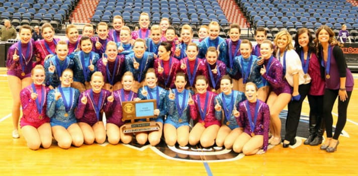 2010-2011 Lightning Dance Team with their trophy, wearing colorful jackets, on the court.