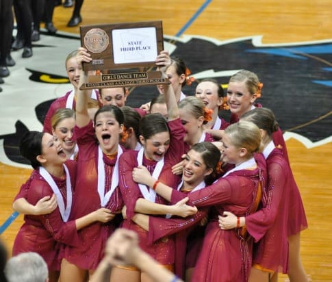 2011-2012 Lightning Dance Team posing with their championship trophy on the court.
